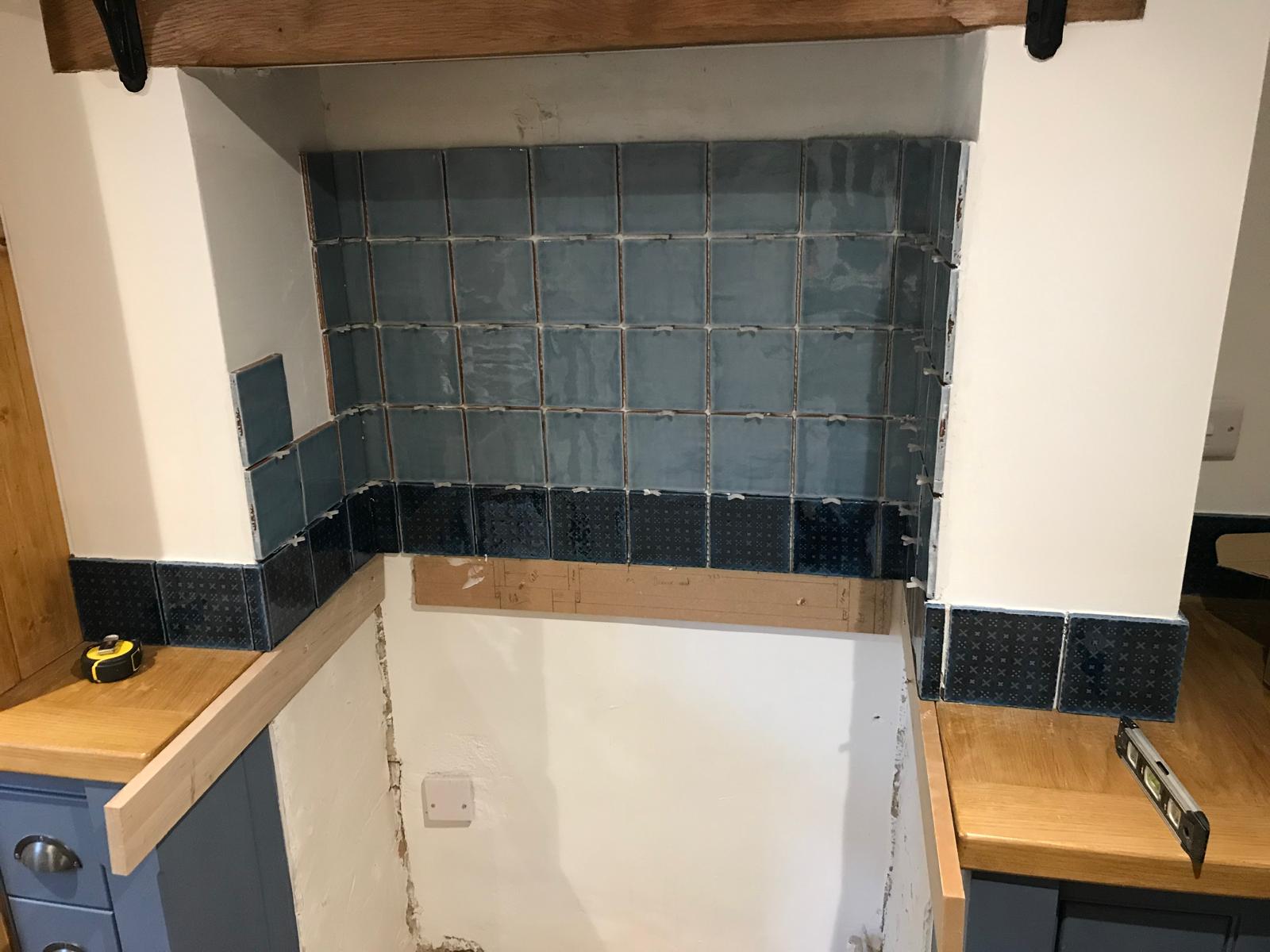 Black and grey square wall tile installation above the cooker for a local kitchen project