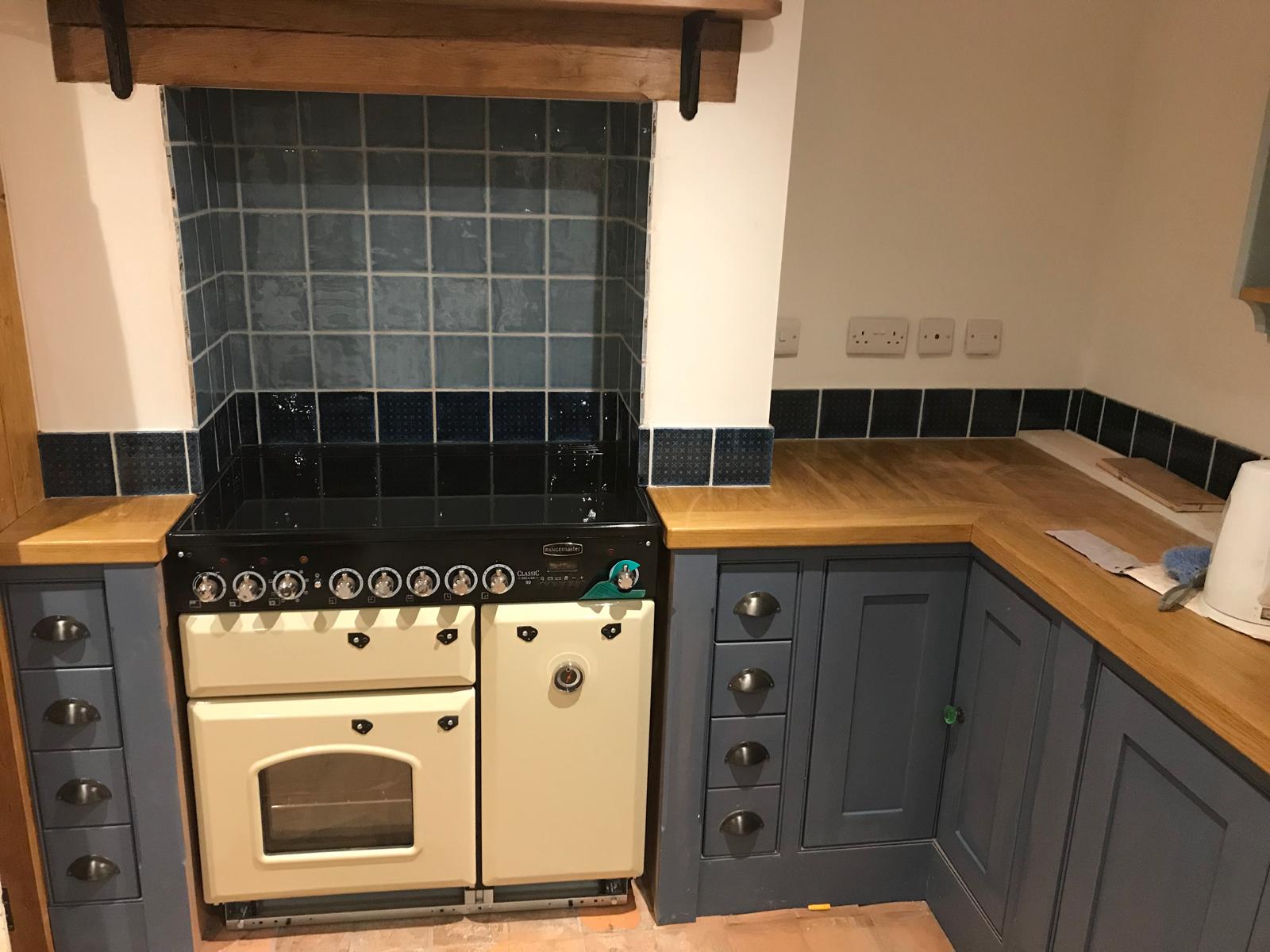 Black and grey wall tile installation with a row of tiles along the worktop for a kitchen project in Kent