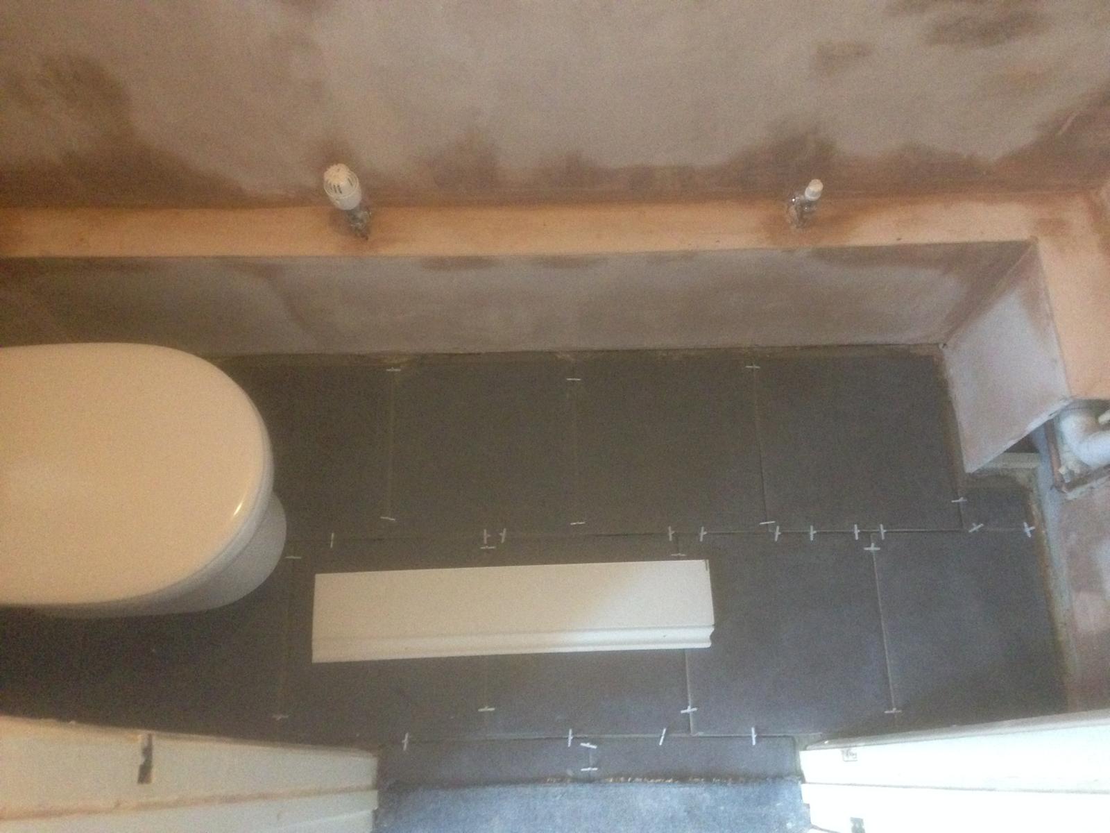 Black floor tile installation in a toilet area for a painting and decorating project 