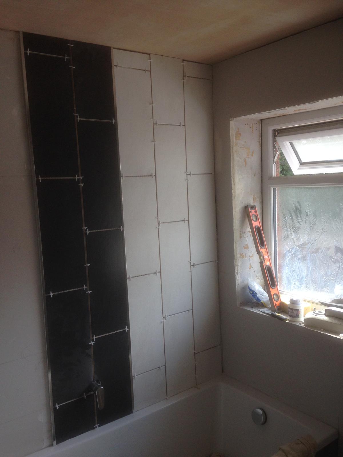 Black wall tile feature above bath 