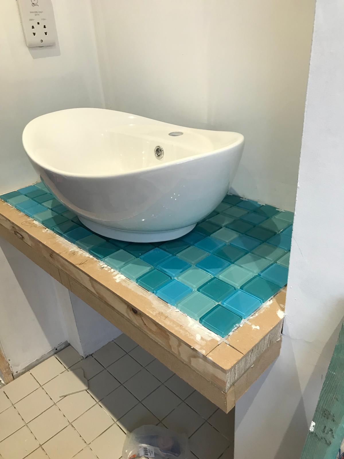 Blue mosaic tiles being installed under sink on local bathroom project