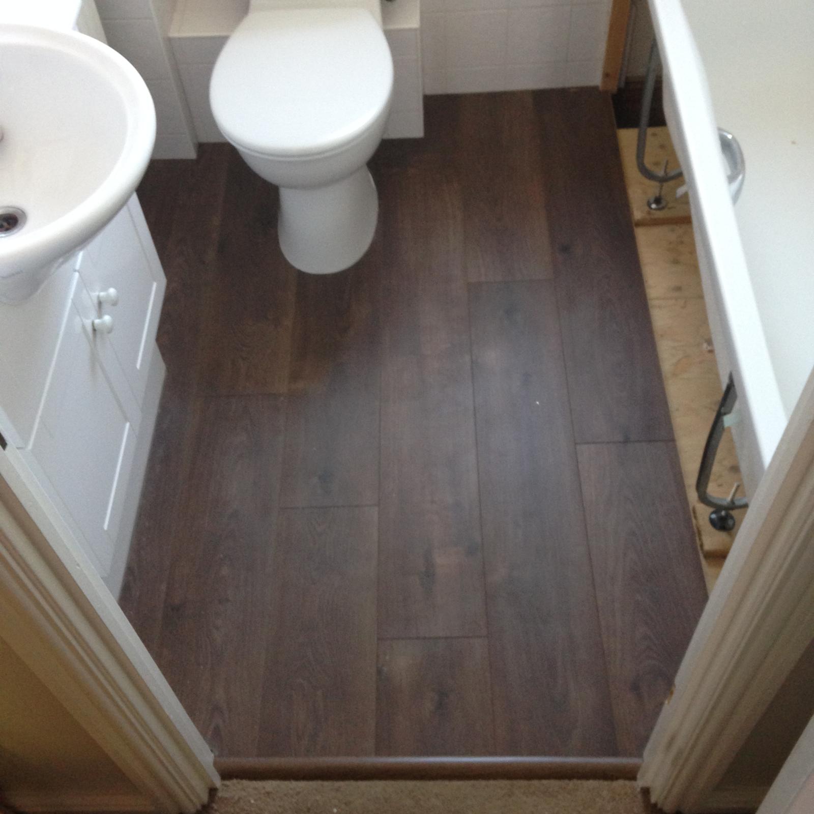 Dark brown laminate floor installation in toilet area for a decorating project in Kent