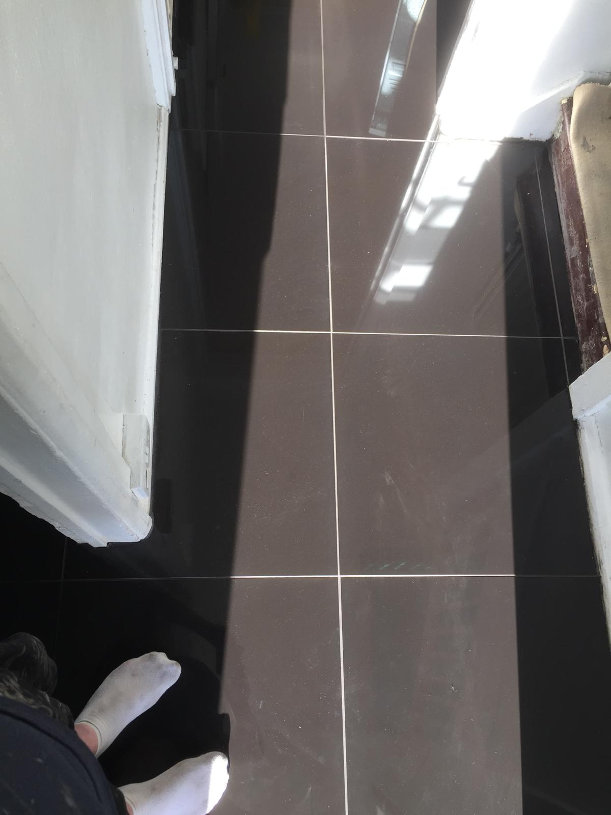 Grey gloss porcelain floor tile installation with a light ground 