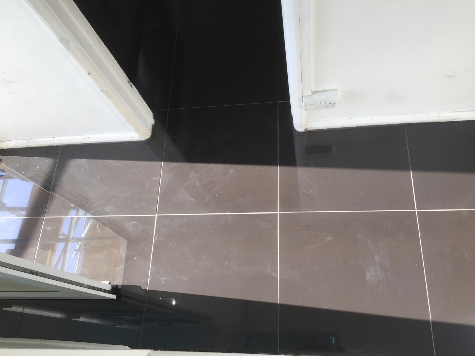 Grey gloss square floor tile installation with light grout