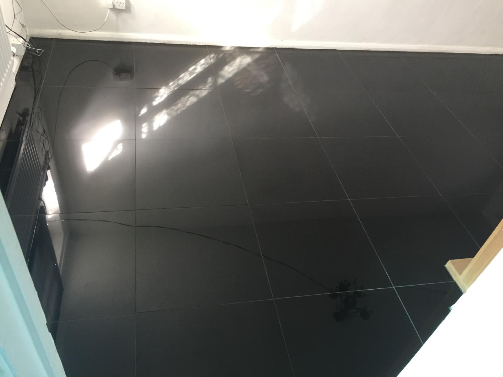 Installation of black gloss floor tiles on a decorating project 