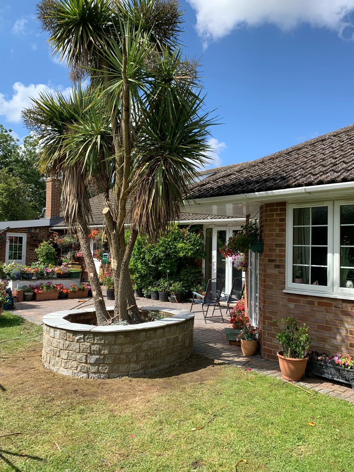 Natural decorative stone wall installation around a tree with a slab top for a local landscaping project in Kent