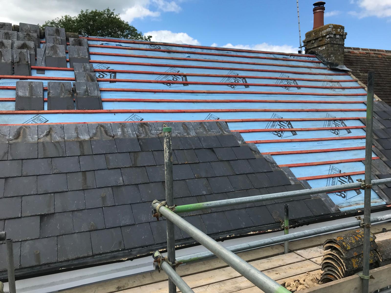 Roof installation project with slate roof tiles being installed