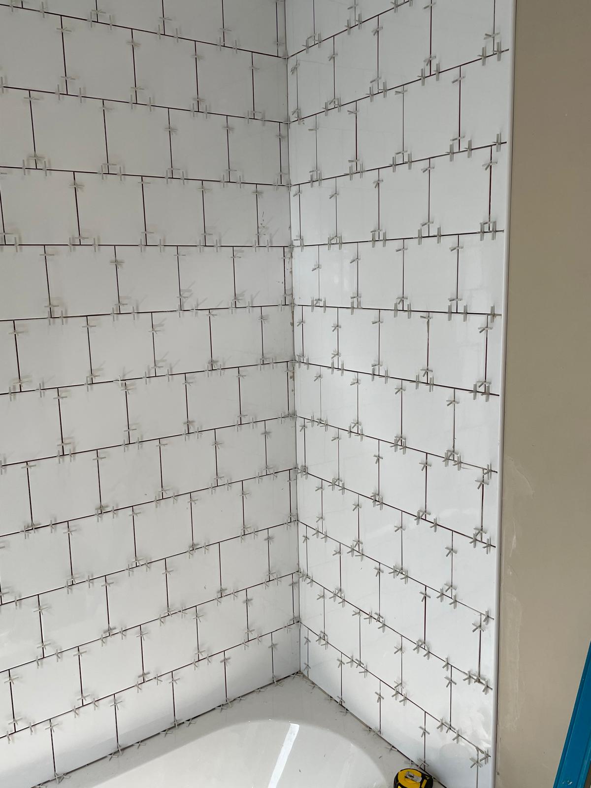 Square white tile installation spaced and adhered to the wall for a bathroom project in Kent 